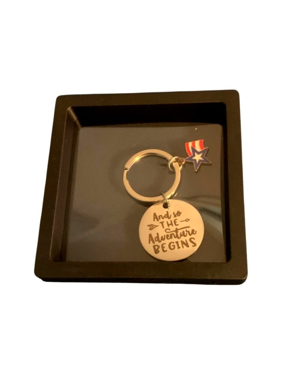 Keychain circular metal with the phrase " And so THE Adventure BEGINS"